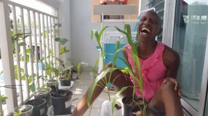 kuwa jasiri (the one) laughs while on the porch interacting with the container garden